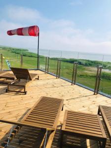 a deck with benches and an umbrella and the ocean at Aitvarai 41 in Svenele