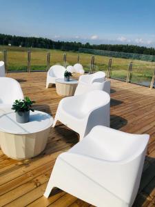 une terrasse en bois avec des chaises et des tables blanches dans l'établissement Aitvarai 41, à Svencelė