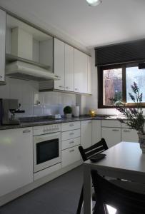 eine Küche mit weißen Schränken, einem Tisch und einem Fenster in der Unterkunft Barcelo al riu in Monistrol de Montserrat