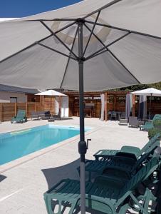 a group of green lounge chairs under an umbrella next to a pool at Les gîtes du petit Marcel in Soudan