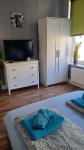 um quarto com uma televisão e uma cama com toalhas azuis em Stadtnah an der Förde 75 2 em Flensburg