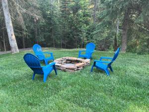 three blue chairs sitting around a fire pit in the grass at Glacier Homestead in Coram