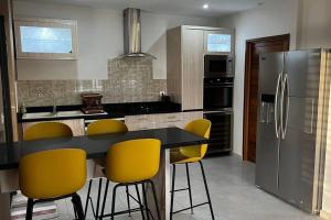 a kitchen with a black counter and yellow chairs at Maya Plage, Villa en bord de mer in Cap Skirring