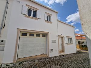 a white house with a garage at Chez Gilbert-Alojamento Local in Alqueidão da Serra