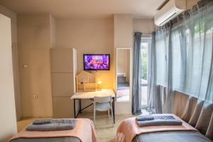 two beds in a room with a desk and a tv at City Center apartament “MARTA” in Varna City