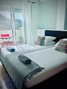 - une chambre avec 2 lits et une fenêtre avec une chaise dans l'établissement La Perla de Frigiliana Suites & Villa, à Frigiliana