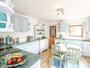 a kitchen with white cabinets and a table and chairs at New Cottage in Bakewell