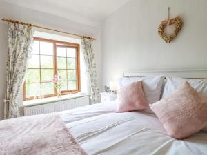 a white bed with pink pillows and a window at New Cottage in Bakewell