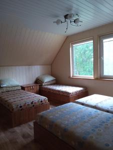 a attic room with three beds and a window at Petronių sodyba in Rukliai