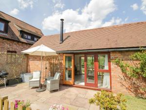 un patio de una casa de ladrillo con sombrilla en The Chicken Shed, en Warwick