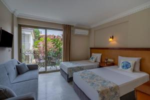 クシャダスにあるRosy Suites Hotelのベッド2台とソファが備わるホテルルームです。
