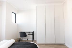 a bedroom with white wardrobes and a chair at City Nest: Heart of Linksfield in Johannesburg