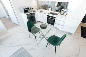 a kitchen with a glass table and two green chairs at City Nest: Heart of Linksfield in Johannesburg