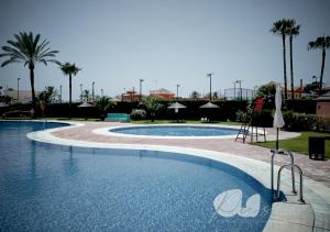een groot zwembad in een resort met palmbomen bij PUSHE Penthouse Playa Granada Beach & Golf 2 in Motril