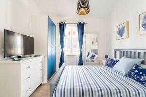 a bedroom with a bed with blue curtains and a television at The Pearl of the sea in Porto Columbu - Perdʼe Sali