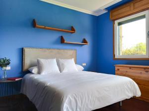 a blue bedroom with a white bed and a window at Villa Remoan in Vilagarcia de Arousa
