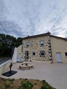 - un bâtiment en pierre avec une table de pique-nique et un parasol dans l'établissement maison à la campagne, à Bromont-Lamothe