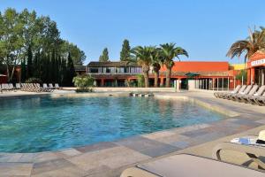 una grande piscina con sedie e un edificio di Appartement résidence vacances amandier a Arles