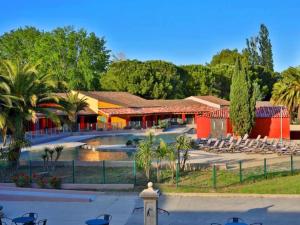 un complexe avec une piscine, des chaises et un bâtiment dans l'établissement Appartement résidence vacances amandier, à Arles