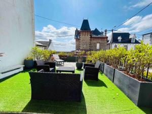 a patio with grass and chairs and a building at La villa Marguerite, face mer avec terrasses in Concarneau