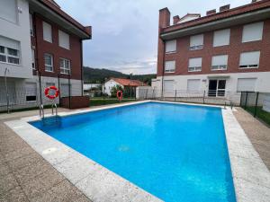 una gran piscina azul frente a un edificio en Apartamento Hoznayo, en Entrambasaguas