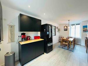 a kitchen with a black refrigerator and a table at La villa Marguerite, face mer avec terrasses in Concarneau