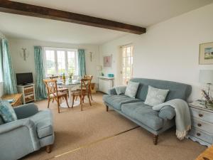 a living room with a blue couch and a table at Lower Woodend Cottage in Ludlow
