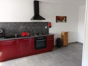a kitchen with red cabinets and a stove at Piwi Thierache 