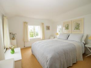 a white bedroom with a large bed and two windows at Lower Woodend Cottage in Ludlow