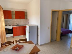 Rousolakos Apartments في باليكاسترون: مطبخ مع طاولة وثلاجة بيضاء