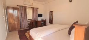 Dormitorio con cama, escritorio y TV en Downtown Virgins Hotel, en Elmina