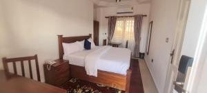1 dormitorio con 1 cama con sábanas blancas y teléfono en Downtown Virgins Hotel, en Elmina