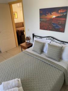 una camera da letto con un grande letto e un dipinto sul muro di Rousolakos Apartments a Paleocastro (Palekastron)