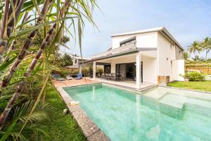 a villa with a swimming pool in front of a house at Villa Ilyana - bord de mer- piscine chauffée in La Saline les Bains