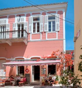 a pink building with people sitting outside of it at Omorfi Poli in Nafplio