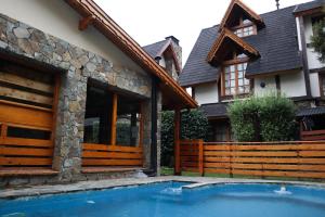 a house with a swimming pool in front of a house at Cabañas Woodland in San Martín de los Andes
