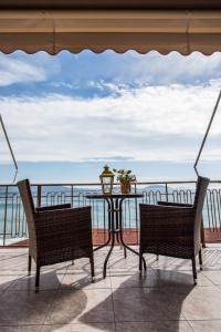 a table and two chairs on a balcony with the ocean at Hotel Assini Beach Tolo in Tolo