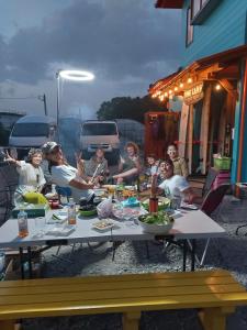 eine Gruppe von Menschen, die an einem Tisch mit Essen sitzen in der Unterkunft Finecamp Guesthouse Share Room 相部屋 in Miyazaki