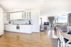 a kitchen and living room with white cabinets at ToVa Apartamentai in Šventoji