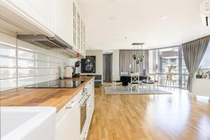 a kitchen with white cabinets and a living room at ToVa Apartamentai in Palanga