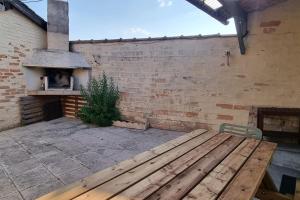een houten bank in een patio met een bakstenen muur bij Relaxing Holiday Home YHH in Lacanau