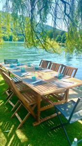a wooden picnic table with two chairs next to a lake at Pieds dans l'eau Private Wellness Bordure de Meuse in Lustin