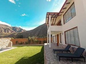 une maison avec deux chaises sur une pelouse avec des montagnes en arrière-plan dans l'établissement Villas de Yanahuara, à Ollantaytambo