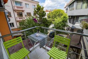a balcony with two green chairs and a table at City Center apartament “MARTA” in Varna City