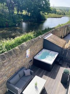 Luxury Canalside Apartment with Hot Tub في Poynton: وجود حوض استحمام ساخن على سطح السفينة بجانب النهر