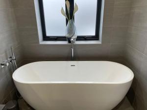 baño con bañera blanca y ventana en Luxury Canalside Apartment with Hot Tub, en Poynton