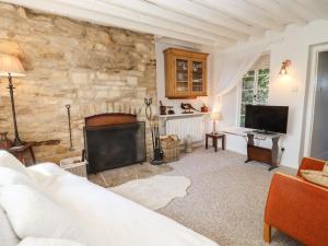 a living room with a fireplace and a stone wall at Woodbine Cottage in Moreton in Marsh