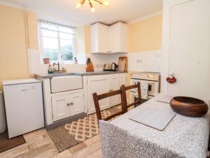 a kitchen with white cabinets and a table with a bowl on it at Woodbine Cottage in Moreton in Marsh