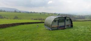 a green trailer sitting in the middle of a field at Little Middop Farm Camping Pods in Gisburn