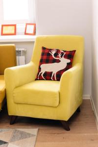 a yellow chair with a deer pillow on it at Уютная и комфортная 3х комнатная квартира со всеми условиями in Uralsk